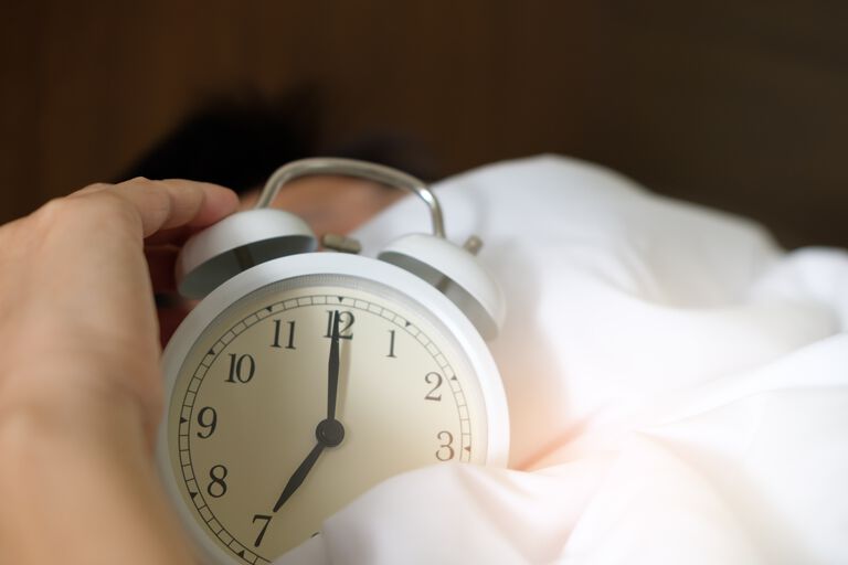 Alarm clock on bedsheets